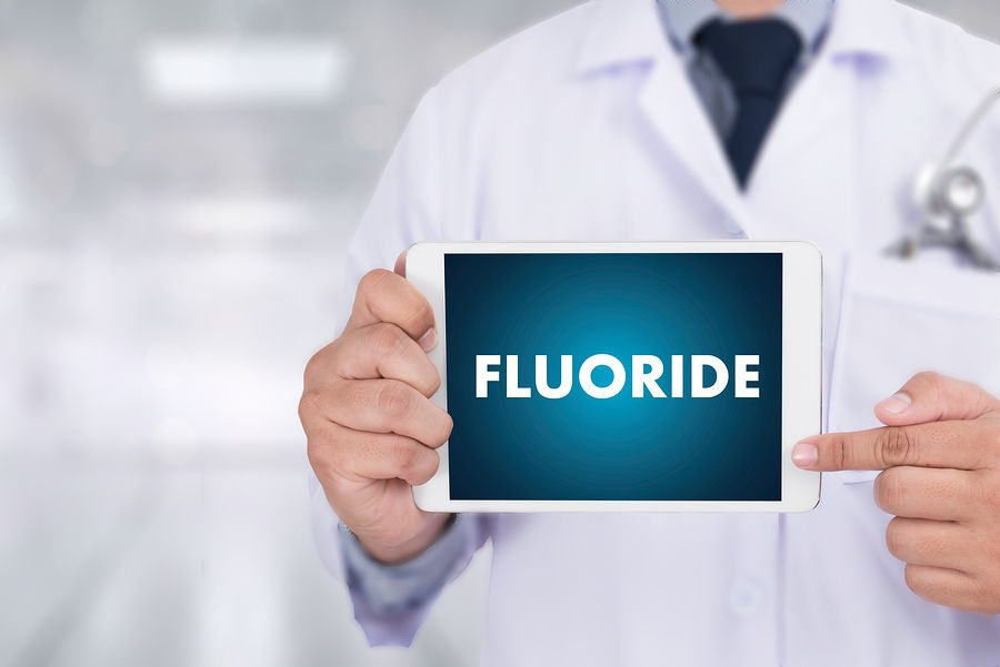 Doctor holding sign with the word FLUORIDE