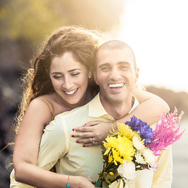Fotografía pre bodas. Novio carga a la novia en su espalda mientras ambos sonríen y la pasan genial en playa Veracruz, Panamá. Fotografía por Ahmed Saturno.