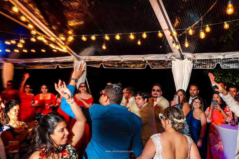 Novios entrando a la pista de baile bajo un gazebo de techo transparente iluminado con luces cálidas de feria, rodeados de sus invitados que los reciben entre gritos y aplausos durante la fiesta de boda en Casa Lourdes, El Valle de Antón, Panamá. Fotografía por Ahmed Saturno.