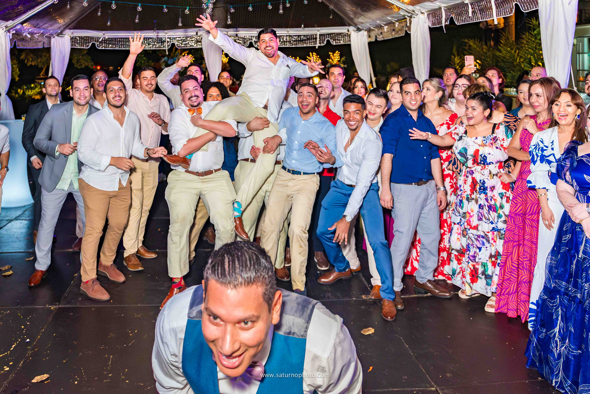 Novio a punto de lanzar la liga mientras los solteros se preparan al fondo y a uno lo cargan en hombros listos para atraparla durante la fiesta de boda en Casa Lourdes, El Valle de Antón. Fotografía por Ahmed Saturno.