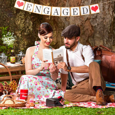 Sesión Preboda al aire libre con temática de picnic vintage. Novios disfrutan leyendo un libro en el césped debajo de un árbol en Clayton, Ciudad de Panamá. Fotografía por Ahmed Saturno