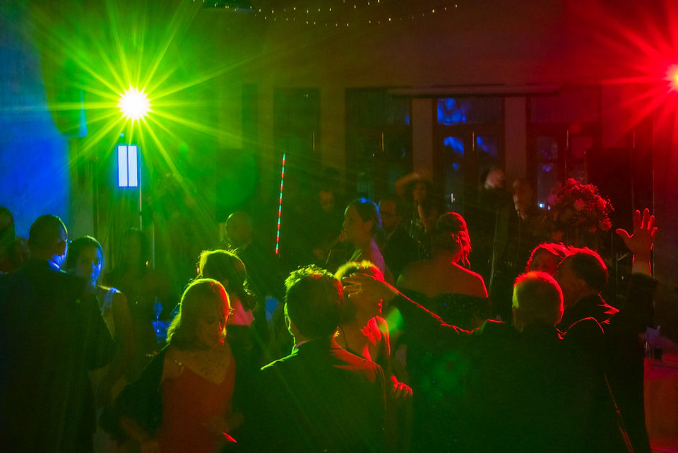 Pista de baile en la recepción de boda iluminada como una discoteca nocturna, con dos luces protagonistas: una luz verde con efecto estelar que dibuja destellos sobre la escena y otra luz roja a la derecha, creando una atmósfera vibrante y festiva mientras los invitados disfrutan la fiesta. Ciudad de Panamá. Fotografía por Ahmed Saturno.