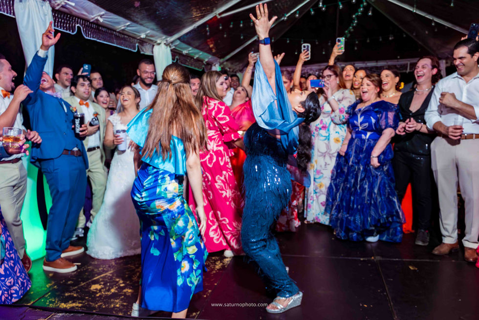 Invitada levantando los brazos y mirando al cielo en señal de triunfo tras ganar el duelo de baile mientras la pista celebra durante la fiesta de boda en El Valle de Antón, Casa Lourdes. Fotografía por Ahmed Saturno