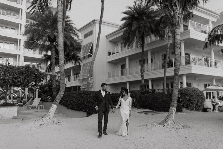 Bride and groom walking on sand before their reception on Seven Mile Beach