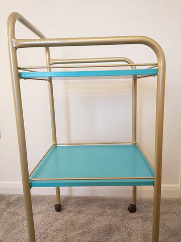 a turquoise and gold cart with two shelves