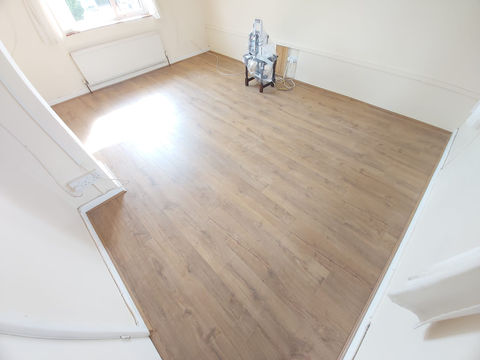 an empty room with a wooden floor and a small table