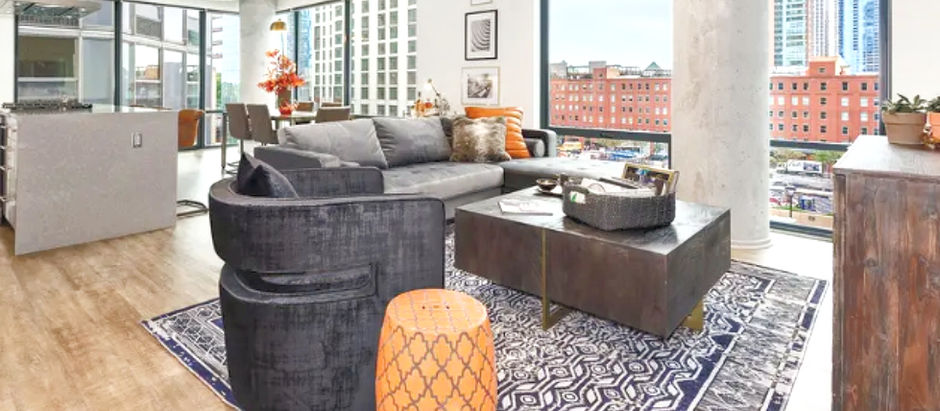Contemporary urban living room with floor to ceiling windows, custom furnishings, and views of downtown chicago.