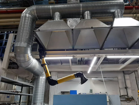 Industrial ventilation system with metal ducts and adjustable arms in a factory.