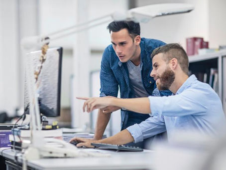 Zwei Männer vor einem Bildschirm am Schreibtisch