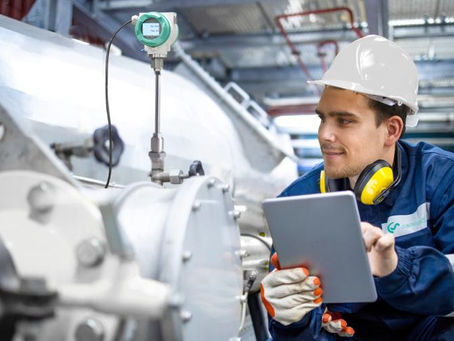 Mann mit Helm und Gehörschutzhörern sitzt vor einer Maschine