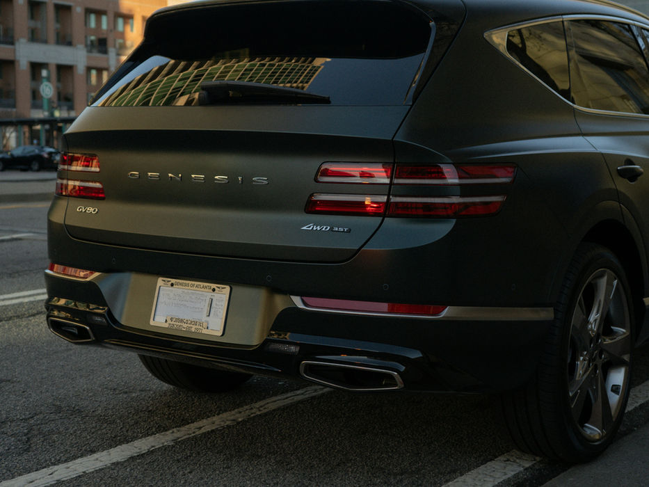 Dark-green Genesis GV80 SUV parked on city street