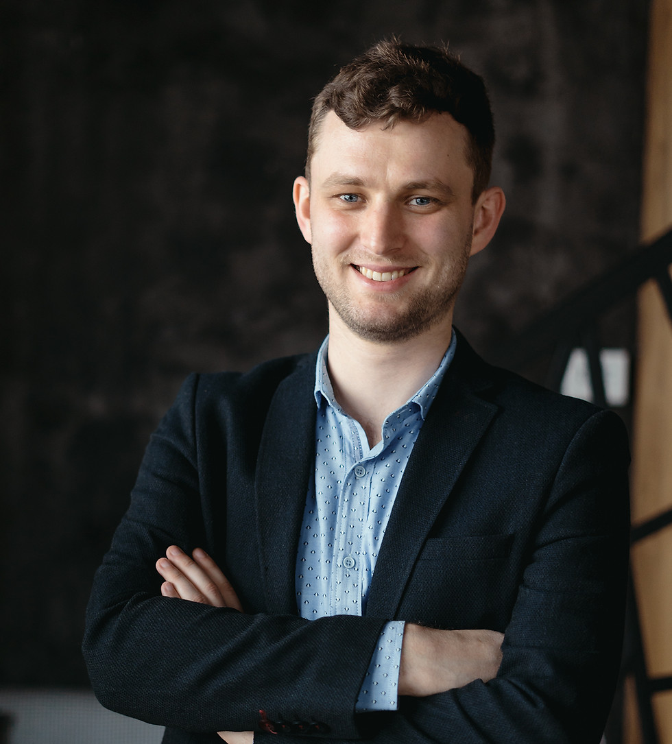 Smiling man in a suit with arms crossed, professional portrait, confident About Us