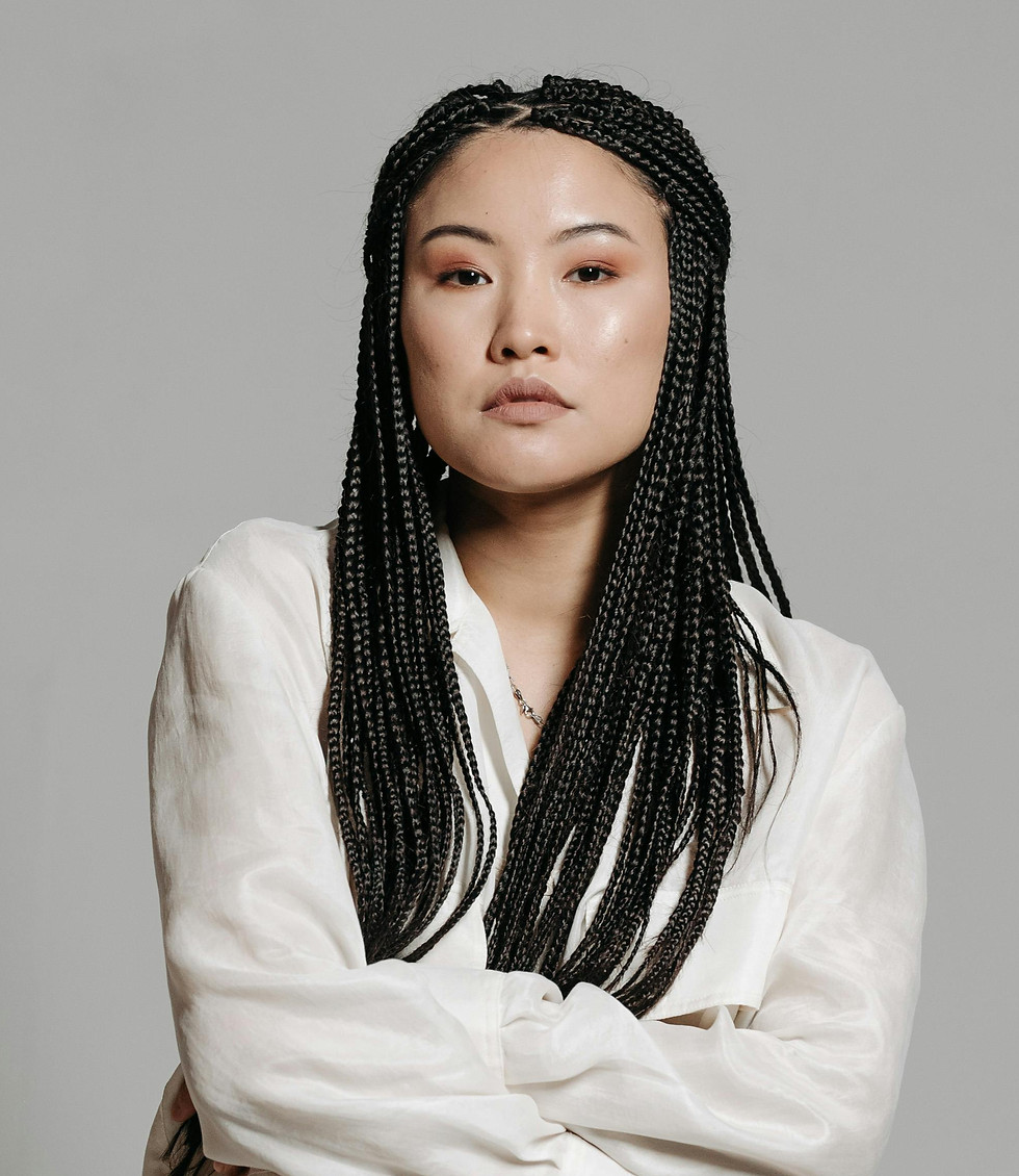 Woman with long braids, arms crossed, wearing a white shirt