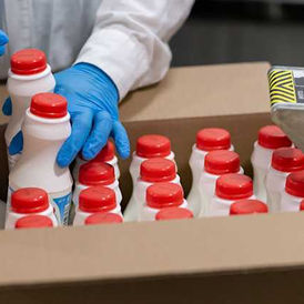 Food manufacturing worker packing beverage bottles at a Canadian processing facility