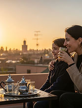 Family enjoying Moroccan tea on a rooftop terrace at sunset, relaxing together with city views during a calm Marrakech family experience