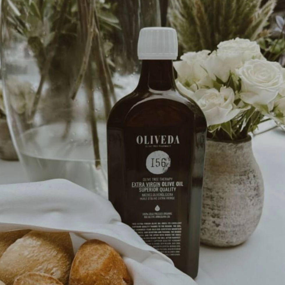 Olive oil bottle next to basket of bread on table with white flowers