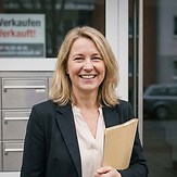 eine blonde Hausbesitzerin blickt stolz in die Kamera