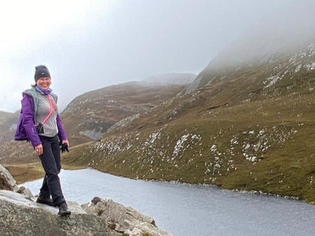Woman standing on a hillside overlooking a lake
