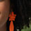 Thumbnail: Woman wearing orange Asala Statement Earring with curly hair and white shirt.