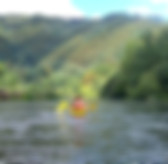A kayak glides smoothly on the calm Montego River, surrounded by lush green hills