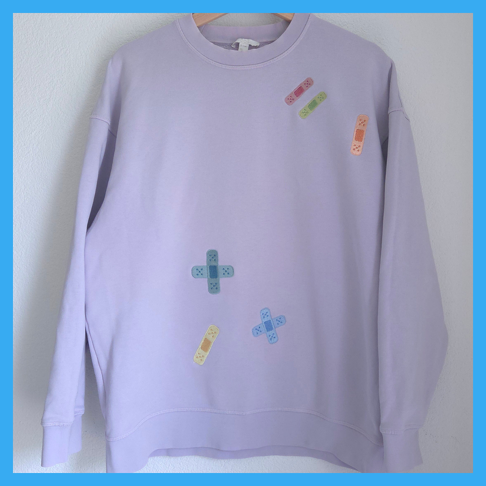 Band aid machine embroidery designs stitched out in multiple pastel colors on a lavender sweatshirt — showing both single pla