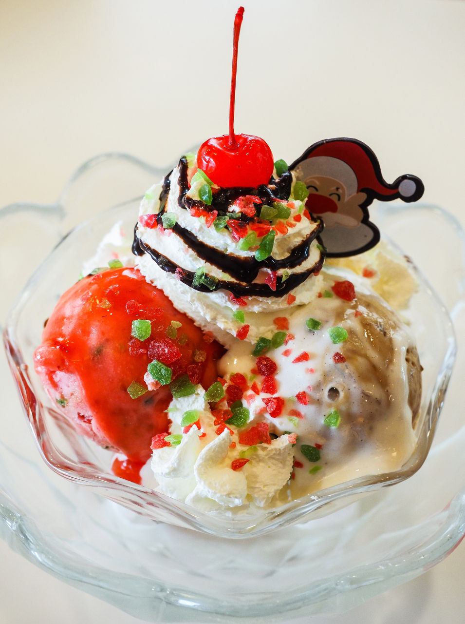 Noir & Nopal ice cream sundae topped with whipped cream, chocolate drizzle, candied sprinkles, and a cherry on top.