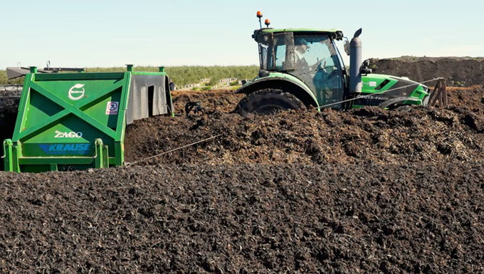 Máquina agrícola a trabalhar atolada quase até ao meio em terra escura