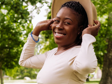 Jazzmine smiling in the park with sun hat and tan jogging set.