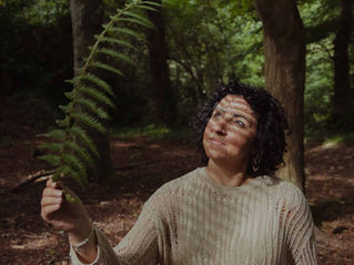 paola in the woods looking at a fern