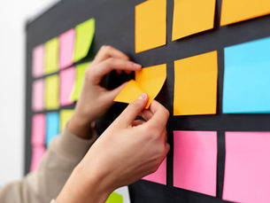 mains-tableau-noir-nombreux-post-its-colores