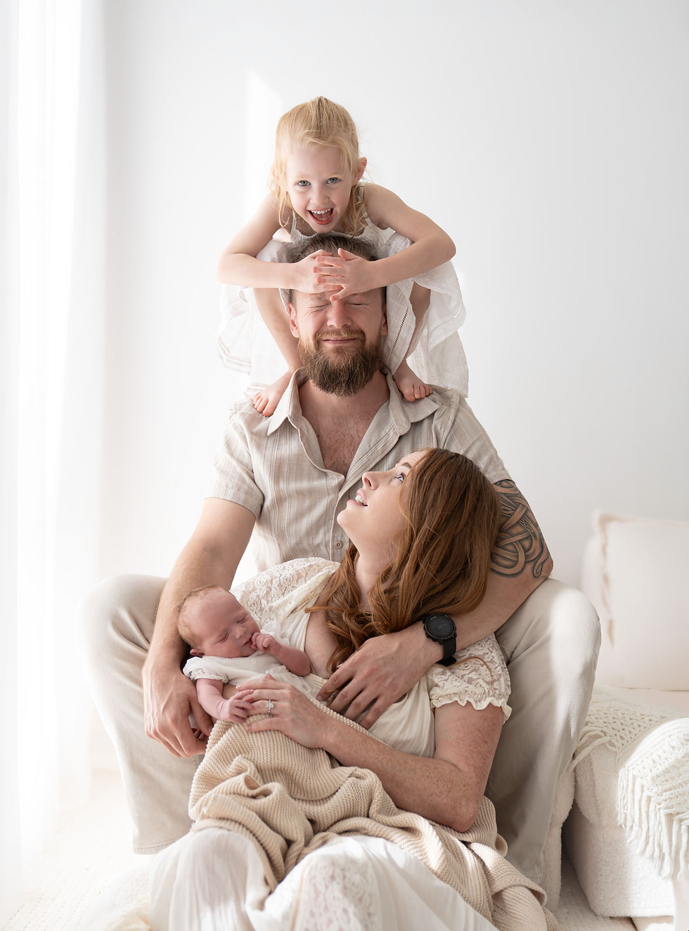 A girl cheekily covers her dads eyes during a family photoshoot in perth