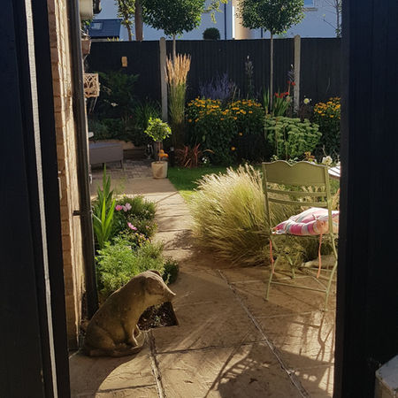 View through a gate to flower beds including trees that screen neighbouring properties windows