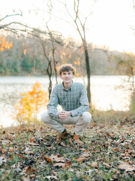 Young man crouching by a lake in autumn