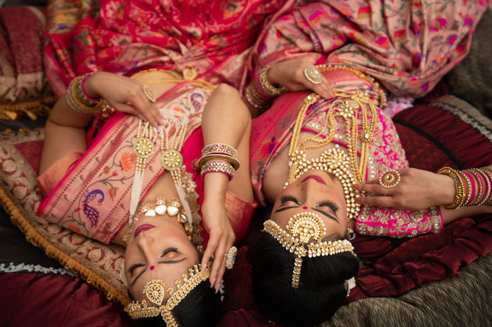 Two brides in ornate saris, glamorous makeup