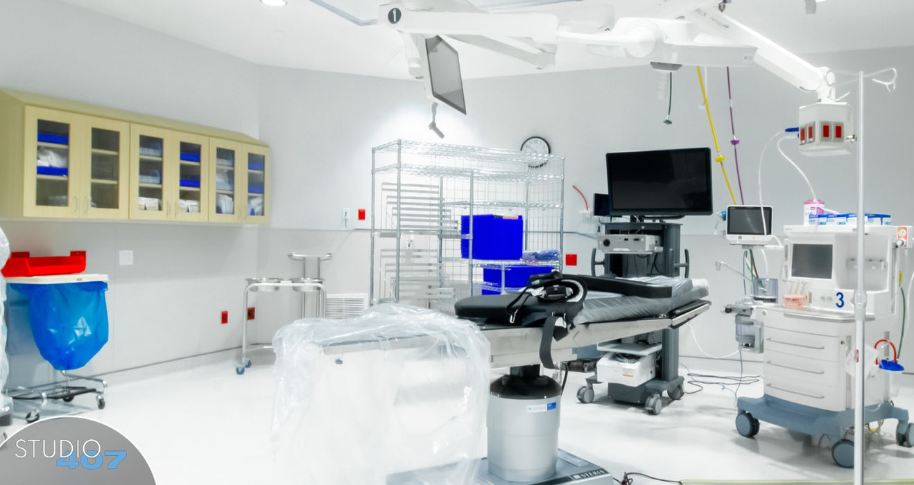 Modern surgical room with medical equipment, monitors, and operating table.