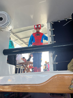 Halloween Kids 1-hour cruise aboard ÜberVida Bermuda on Saturday, October 31, 2026, featuring a fun superhero-themed afternoon with children in costumes, Halloween decorations, music, and family-friendly activities on the water.