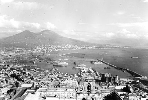 Panorámica en blanco y negro del puerto y los edificios de Nápoles, con el Vesubio al fondo.