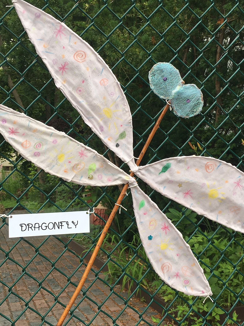 A willow branch dragonfly attached to the Growing Center fence.