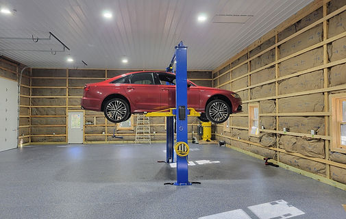 Red car on a vehicle lift inside a newly wired metal garage in King George, Virginia