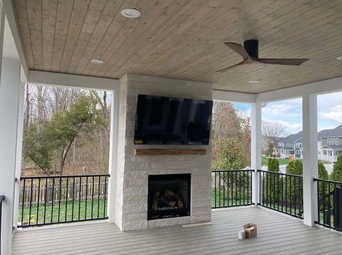 Light stone fireplace centers the image. Featuring a wood plank matching the tone of the planed ceiling and an inset square fireplace strike a balance between rustic and contemporary.