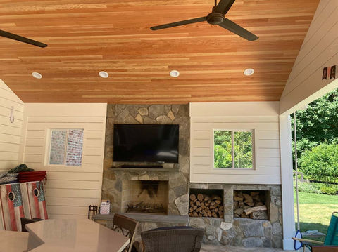 Cozy and Modern indoor porch with a luxurious wood-storing fireplace. Wood paneled- ceilings feel cozy while shiplap walls keep it modern.