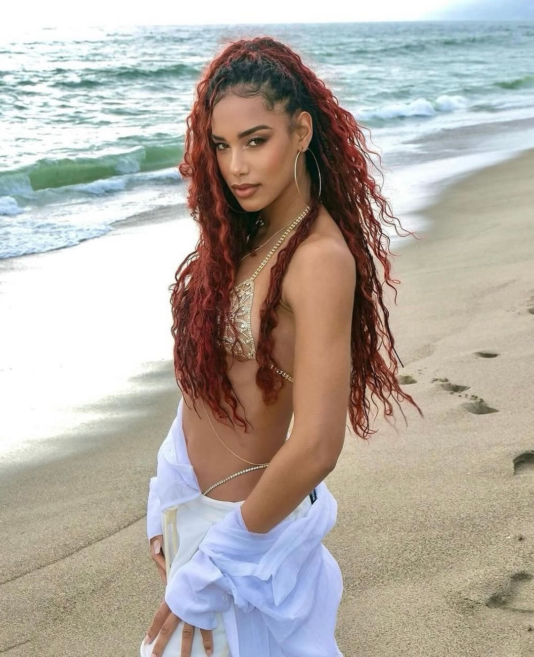 Model posing on the beach wearing handmade gold crystal bra floral design