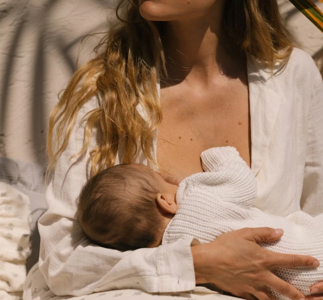 Mutter stillt ihr Baby, ein zärtlicher Moment im hellen Licht.