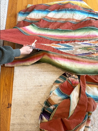 an arm cutting strips in a vintage blanket