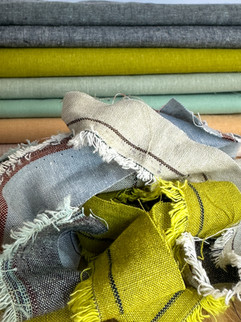 a pile of fabric selvedge scraps in green, blue and tan