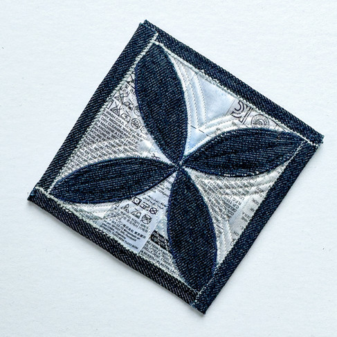 scraps of denim appliqued onto a card on top of jeans labels