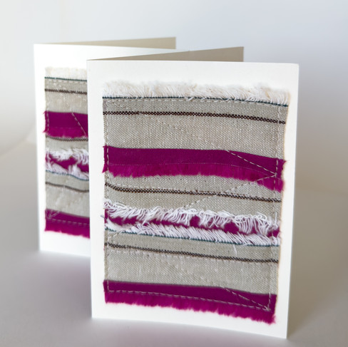 Strips of tan and pink fabric selvedge sewn together like a mini quilt and then sewn onto cardstock