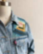 the front of a Levi's denim jacket with a small log cabin quilt block sewn on it