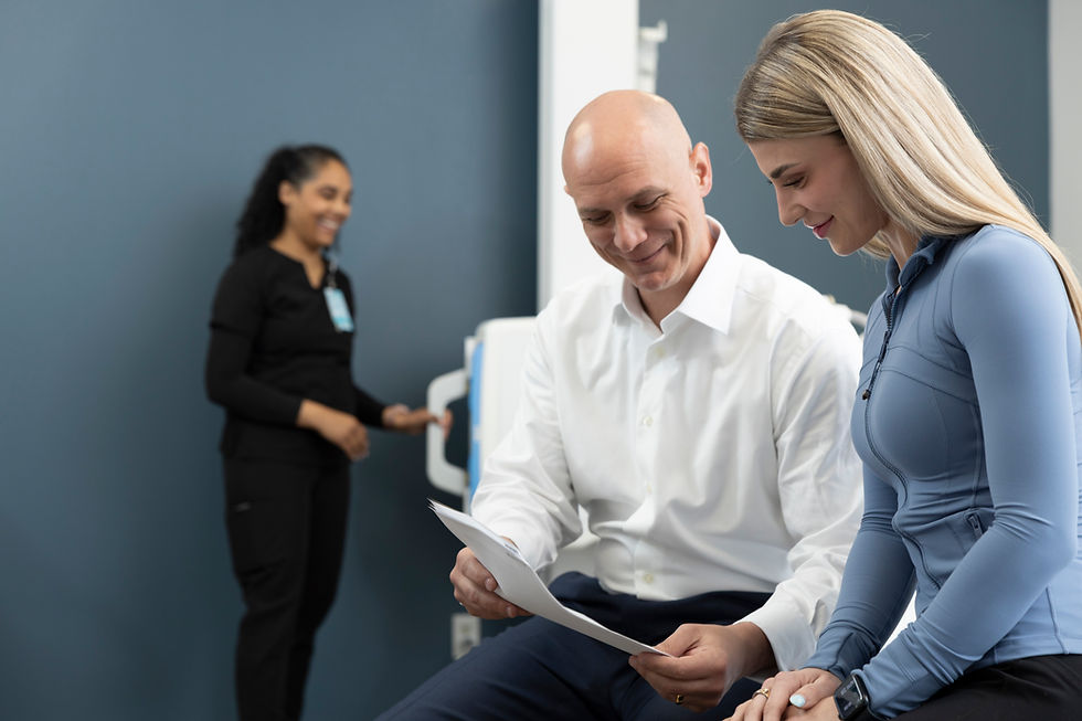 Dr. Justin Faye reviewing results with a patient focused on sports medicine care, with a staff member assisting in the back.
