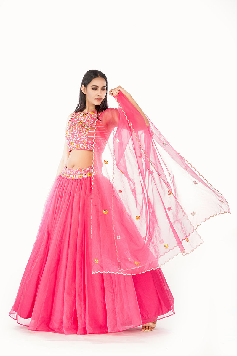 Model wearing a hot pink lehenga with mirror and multi-thread embroidery,